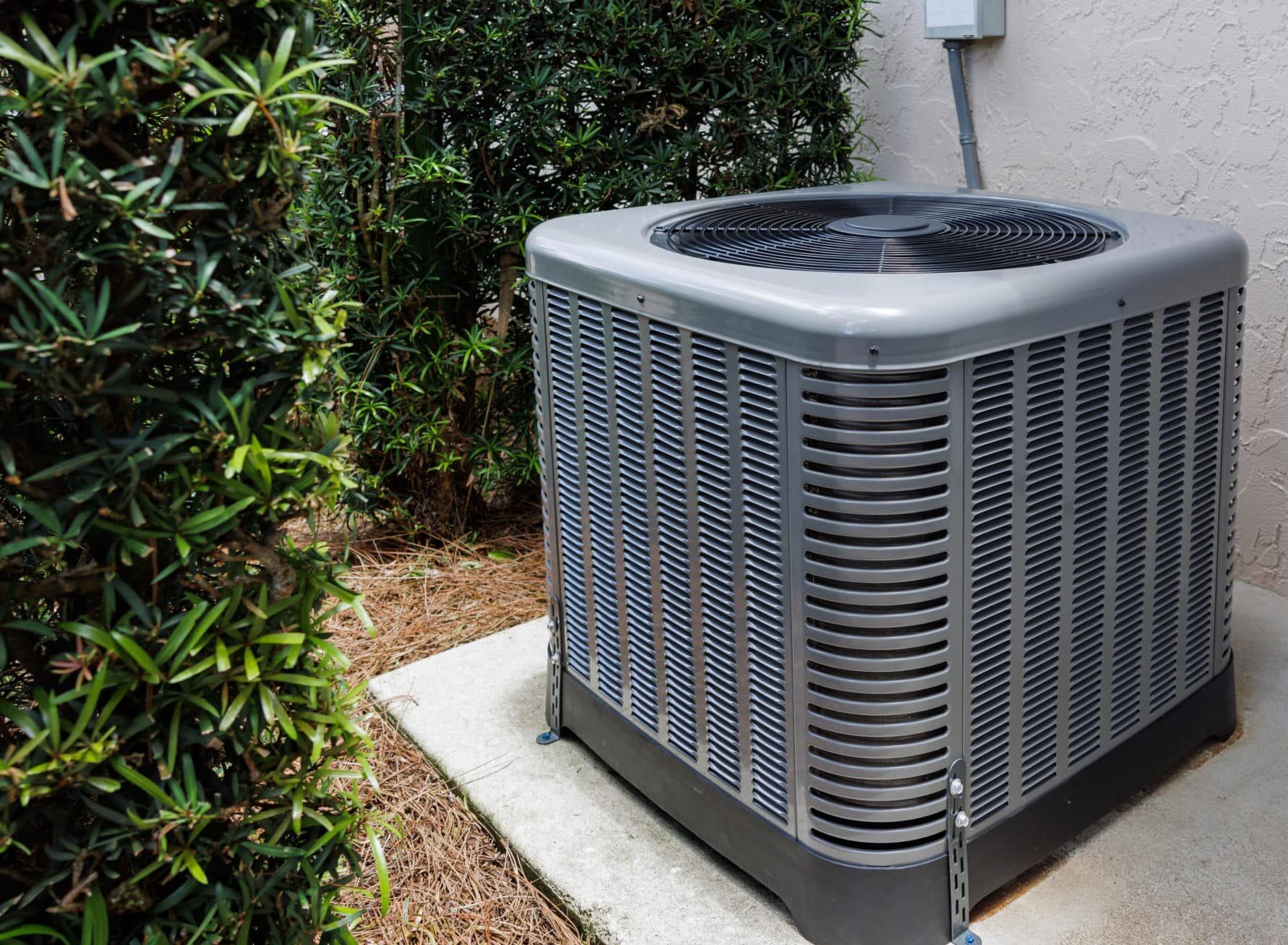 HVAC technician testing electrical components on malfunctioning outdoor condenser unit