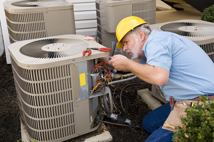 Experienced HVAC technician inspecting components and airflow for system performance